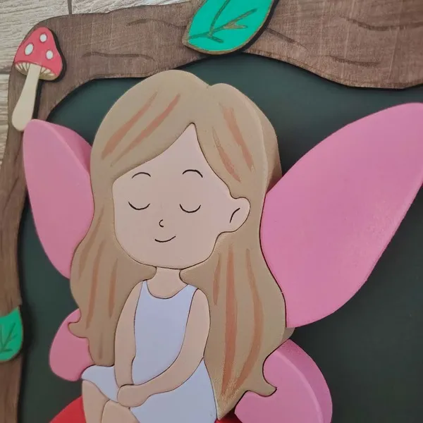 Détail d’une fée aux ailes roses sur un cadre décoratif en bois