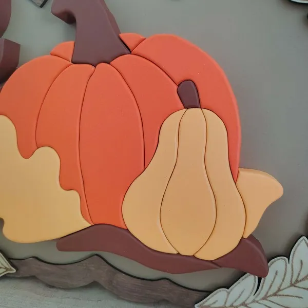 Détail d’un cadre décoratif automnal en bois avec citrouille et courge en relief