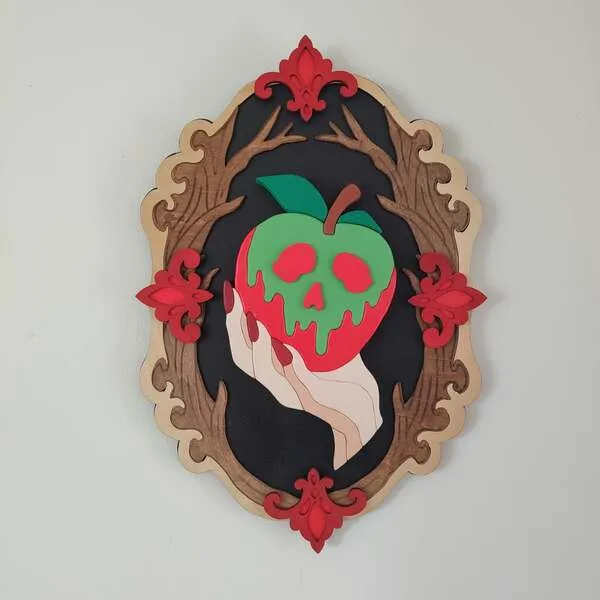 Cadre décoratif gothique en bois avec pomme empoisonnée rouge et verte tenue par une main