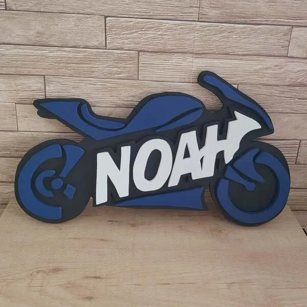 Plaque de porte moto personnalisée en bois noir et bleu avec le prénom Noah en lettres blanches en relief.