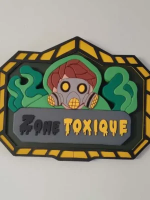 Plaque décorative Zone Toxique en bois avec personnage portant un masque à gaz, fumées vertes et bordure noire et jaune.