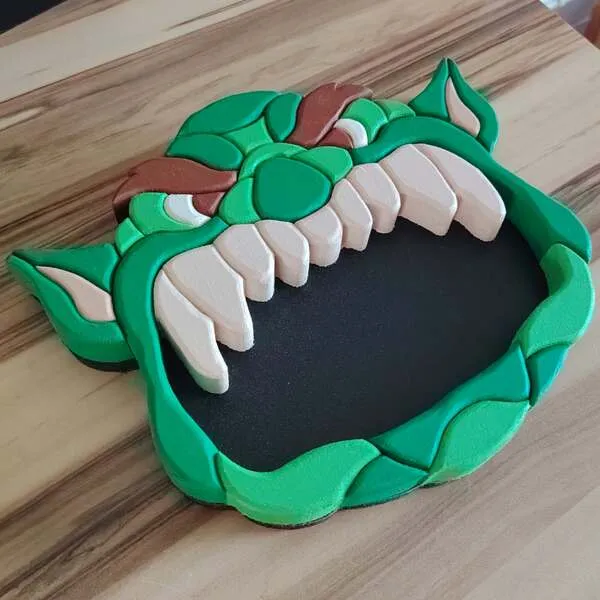 Plateau vide-poche ogre en bois vert avec grande bouche noire et dents blanches vu en perspective